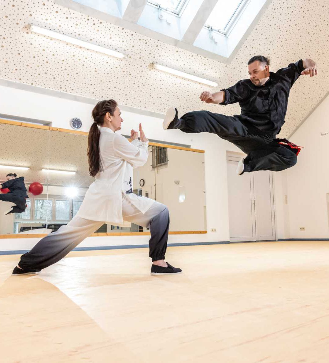 Kung-Fu-Trainer zeigt einen Sprungkick beim gemeinsamen Training.